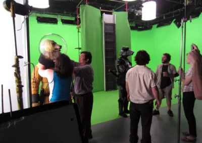 5 crew people helping two actors prepare for a scene they need to wear space suits for.